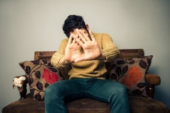 Man sitting on a sofa and is hiding his face