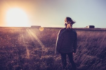 Woman standing in a field at sunset
