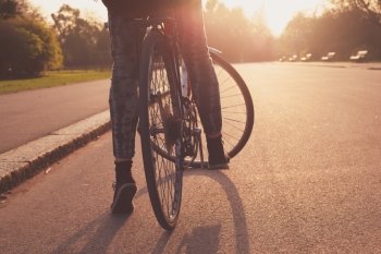 A young woman is cycling into the sunset in the park