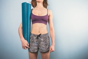 Athletic young woman is holding a yoga mat