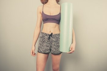 Athletic young woman is holding a foam roller for exercise