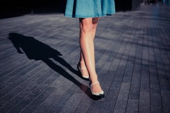 A young woman in retro shoes is walking on the street on a sunny day