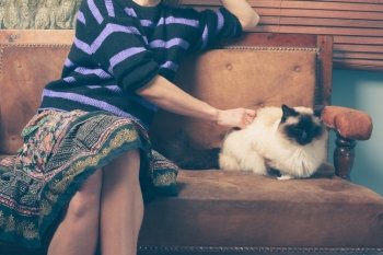 A young woman is sitting on a sofa with her cat