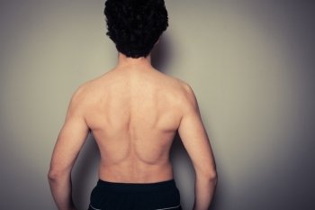 Rear view shot of athletic young man flexing his muscles