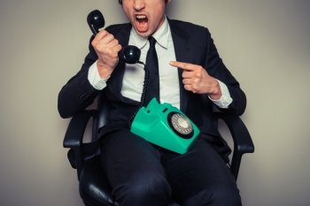 Angry businessman in office chair is on the phone