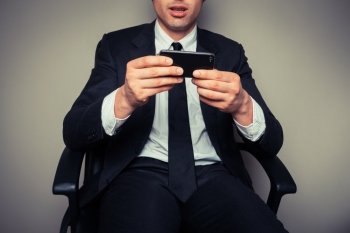 Young businessman sitting in an office chair is using his smart phone