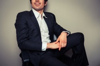 A happy young businessman is sitting in a relaxed pose
