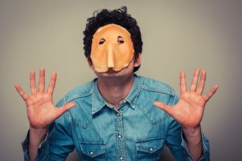 Young man has cut eyeholes in a pancake and is wearing it on his face