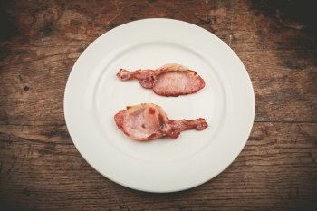 Two rashers of bacon on a white plate