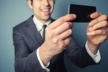 Young businessman is taking a selfie with his smart phone