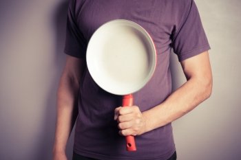 Closeup on a young man holding a frying pan