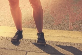 Closeup on a young woman’s legs as she is standing in the street