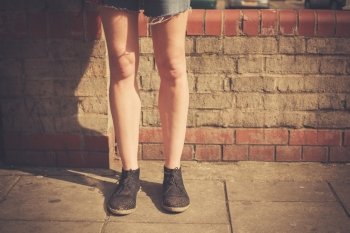 Closeup on a young woman’s legs as she is standing in the street on a sunny day