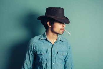 A young cowboy is smoking a cigarette
