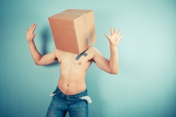A young man is standing with a cardboard box on his head