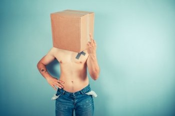 A young man with a cardboard box on his head is displaying an obscene gesture