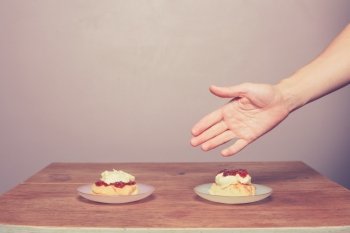 A hand is placing cream teas on a table