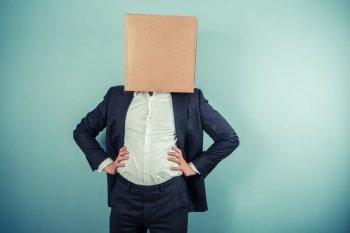A businessman is standing around proudly with a cardboard box on his head