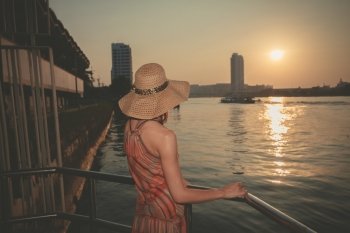 A young woman is admiring the sunset over the river in Bangkok, Thailand
