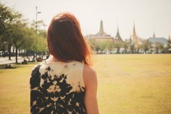 A young woman is standing in a park near the royal palace in Bangkok Thailand