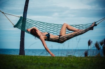 A young woman is relaxing in a hammock by the sea