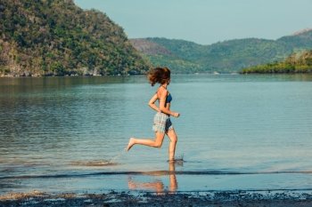 A young woman is runing on a tropical beach