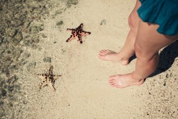 Two starfish on the beach and the feet of a young woman