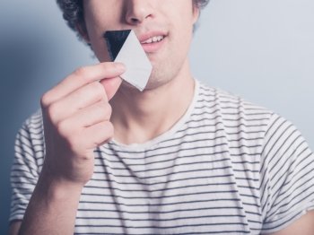 A young man is removing a piece of tape that has been covering his mouth