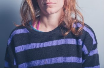 A young woman is wearing a stripey purple and black jumper