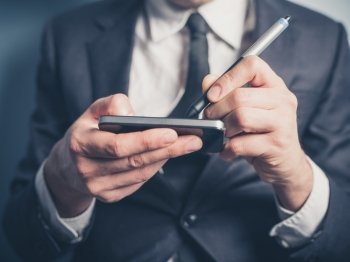 The hands of a businessman as he is using an electronic pen on his smartphone