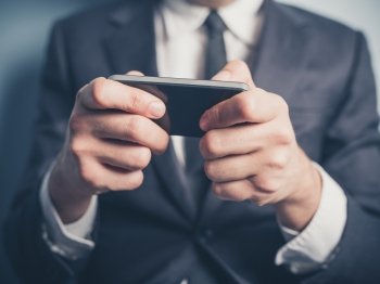 Close up on a businessman’s hands as he is using a smartphone