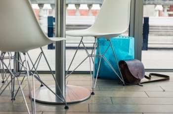 An abandoned shoulderbag and bag of shopping by the window in a cafe