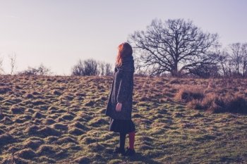 A young woman with red hair is walking in the countryside on a winter day