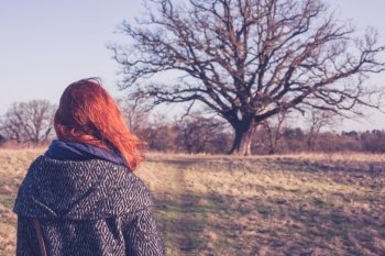 A young woman with red hair is walking in the countryside on a winter day
