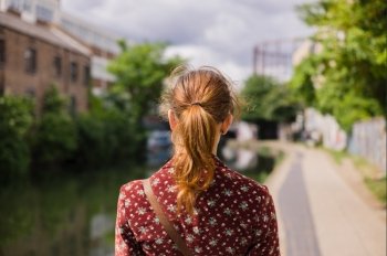 A young woman is standing by a canal on a sunny spring day
