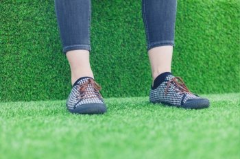 The legs and feet of a young woman resting on some astro turf