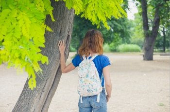 A young woman is standing under a tree in the park