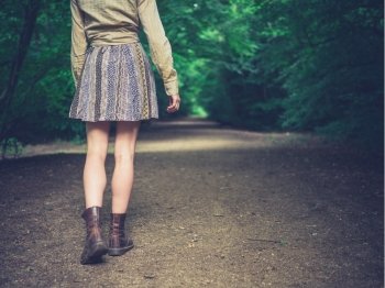 A young woman is walking on a road in the forest