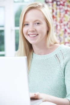 Smiling Teenage Girl Using Laptop At Home