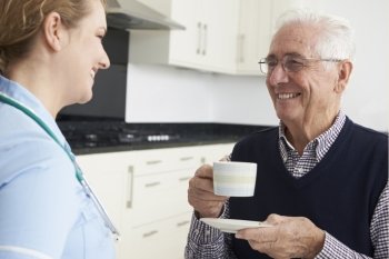 Nurse Chatting With Senior Man During Home Visit