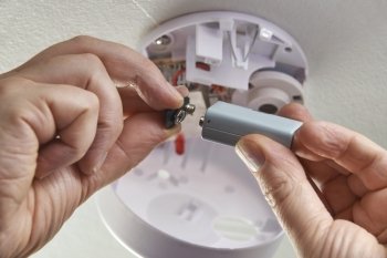 Close Up Of Replacing Battery In Domestic Smoke Alarm