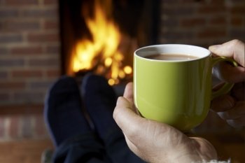 Man With Hot Drink Relaxing By Fire