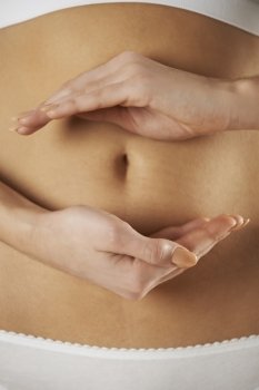 Close Up Of Woman Holding Hands In Front Of Stomach In Circular Shape