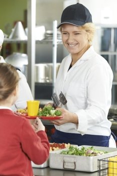 Famale Pupil In School Cafeteria Being Served Lunch By Dinner Lady