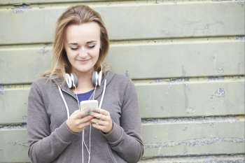 Teenage Girl Wearing Headphones And Listening To Music In Urban
