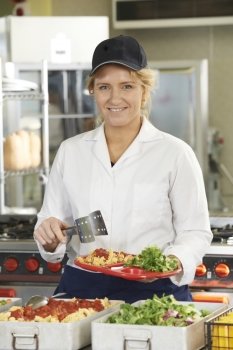 Portrait Of Dinner Lady Serving Meal In School Cafeteria