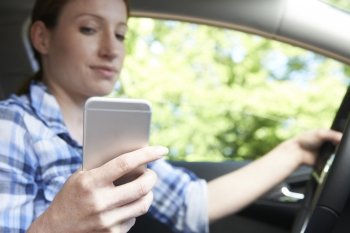 Woman In Car Texting On Mobile Phone Whilst Driving