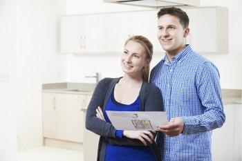 Happy Couple Looking At Details For Property They Hope To Buy