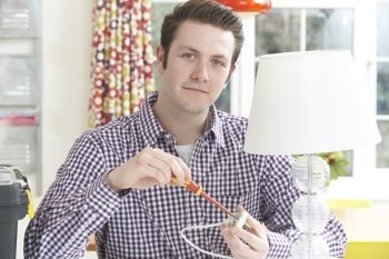 Man Wiring Electrical Plug On Lamp At Home