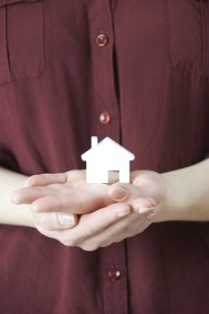 Woman Holding Model House In Palm Of Hand